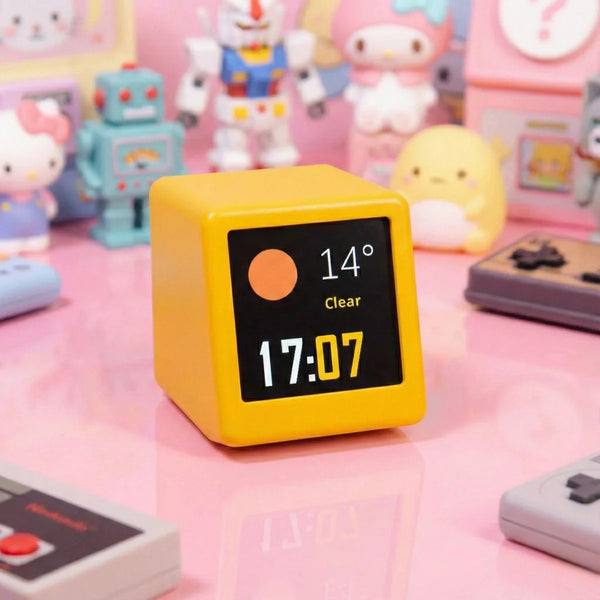 Yellow digital clock with a black screen displaying time and temperature, surrounded by colorful toys on a pink surface.
