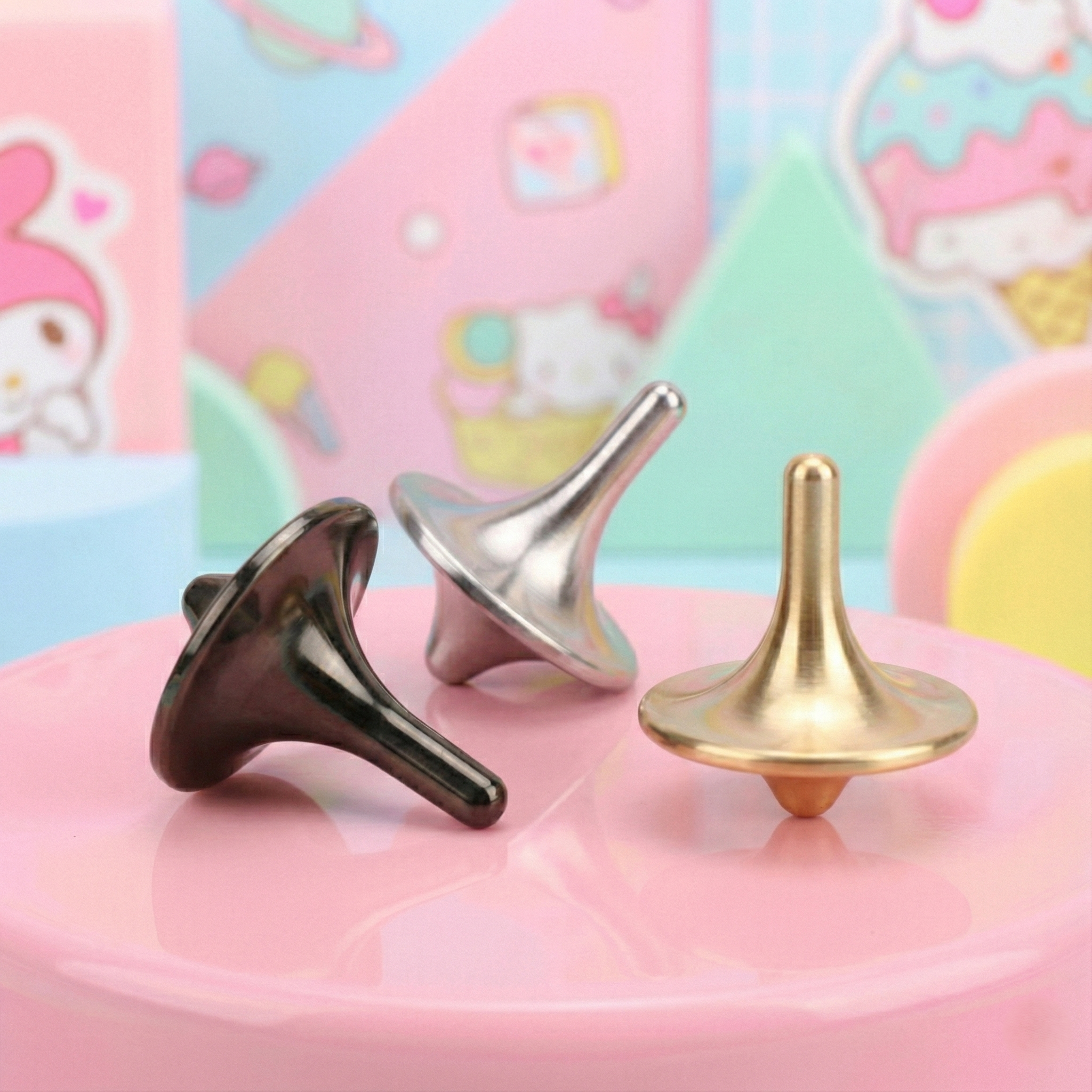 Three metallic spindles in black, silver, and gold on a pink surface with a colorful, cartoon-like background.