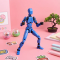 Blue robot toy on a pink surface with stationery items and plants